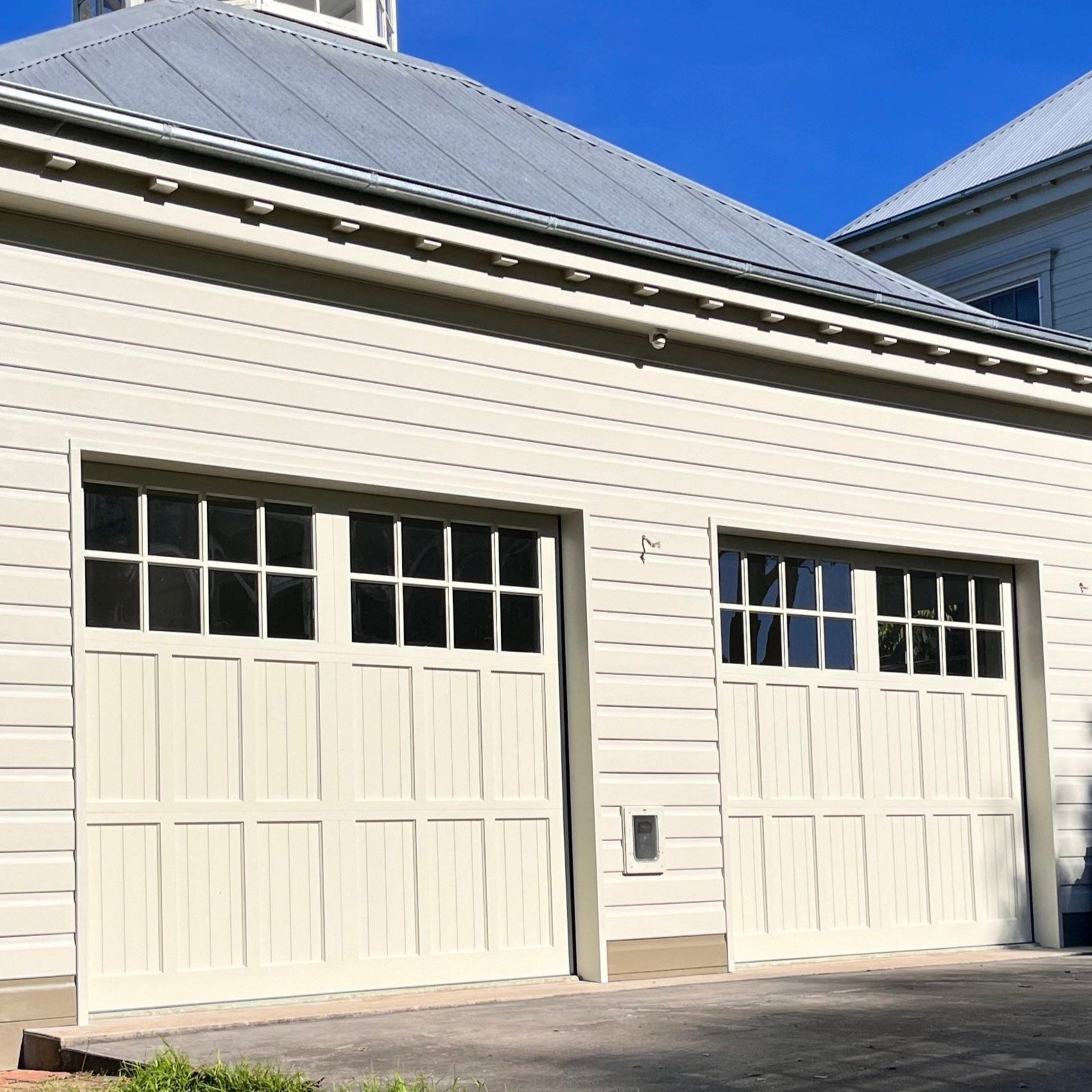 A Hamptons-style sectional garage door is installed with a clear blue sky in the background.